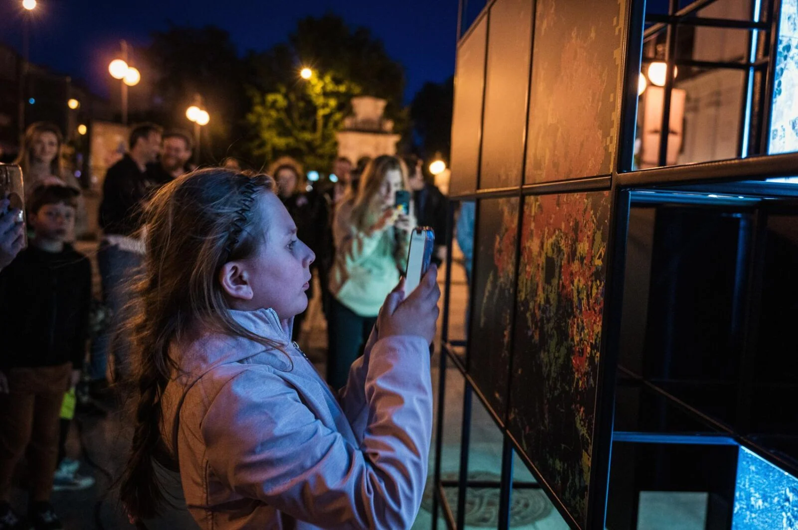 Visitor raising a smartphone towards a Direction Earth/Space panel while others watch.