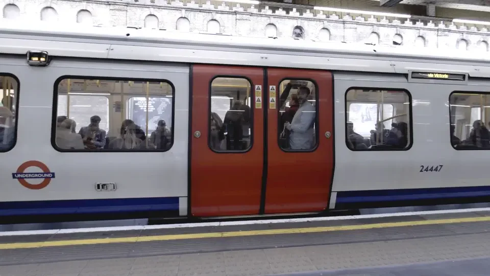 London Underground train standing beside a station platform.