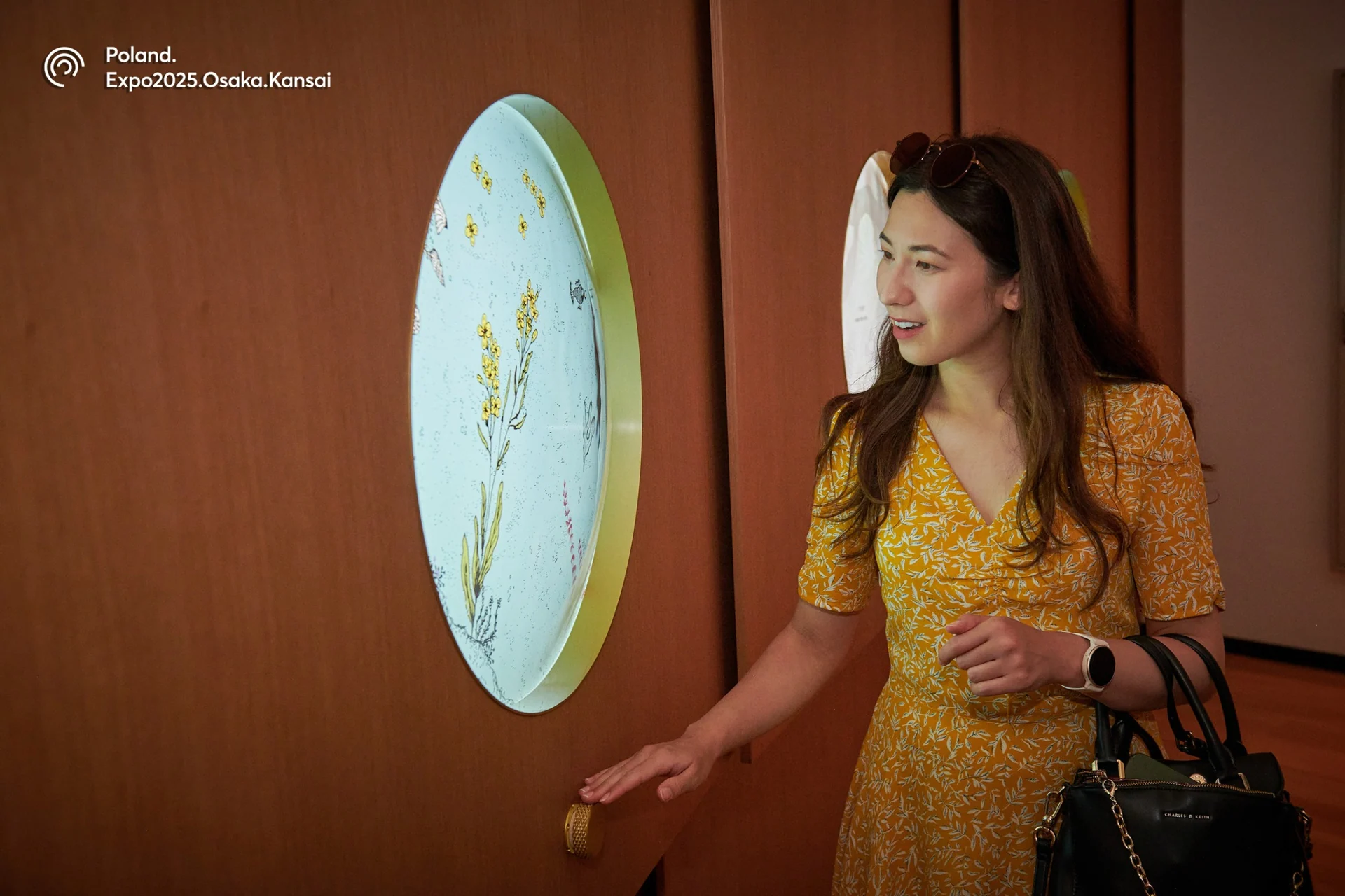 Visitor using a control beneath a circular botanical display in the 7herbs installation.