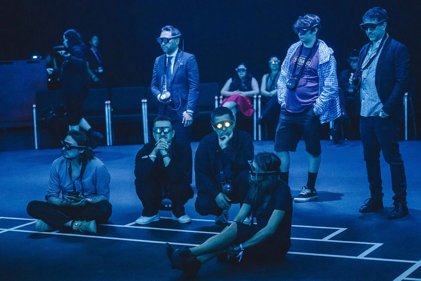 Kagami audience members wearing mixed reality headsets under blue stage lighting.