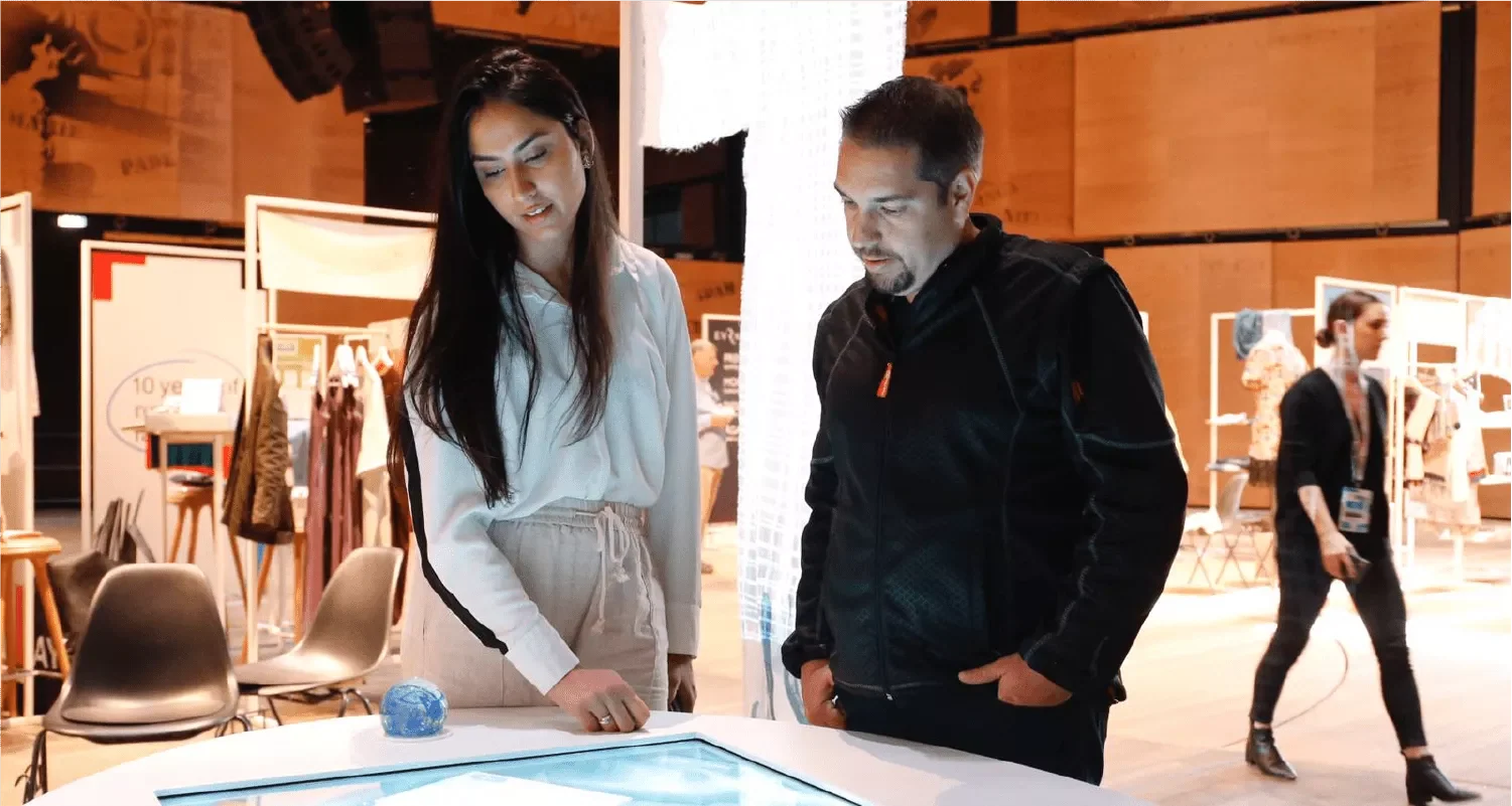 Two visitors using an illuminated interactive table at the WaterAid experiential installation.