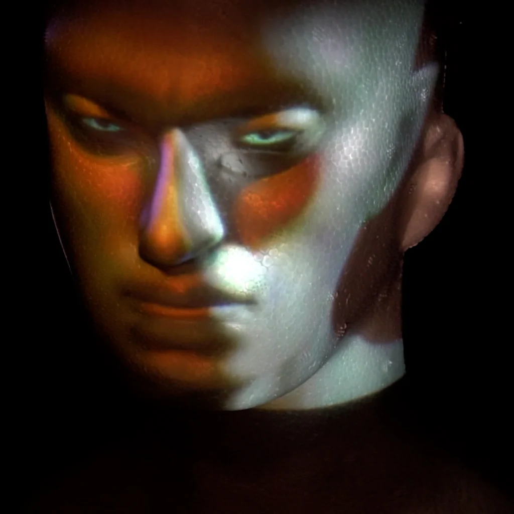 Coloured facial imagery projected onto a sculpted head in the AI projection-mapping experiment.