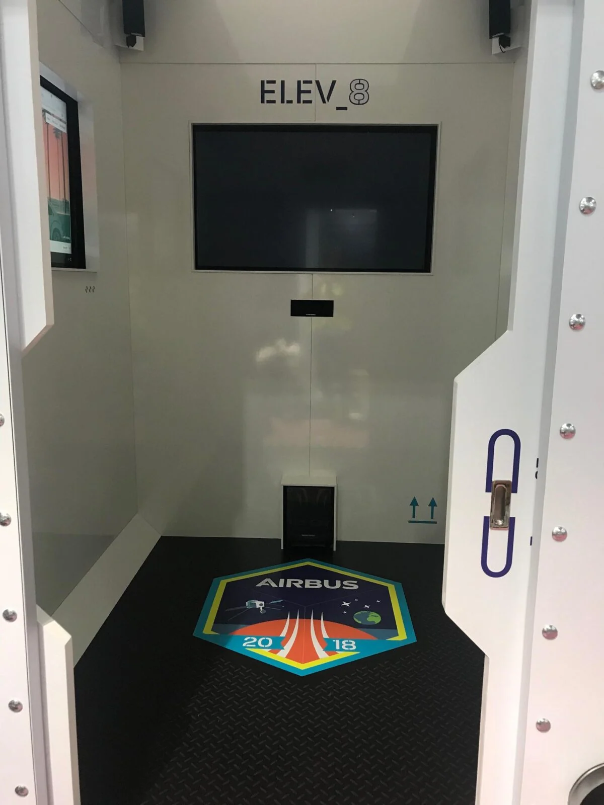Interior of the Airbus ELEV8 cabin with a wall screen and branded floor panel.