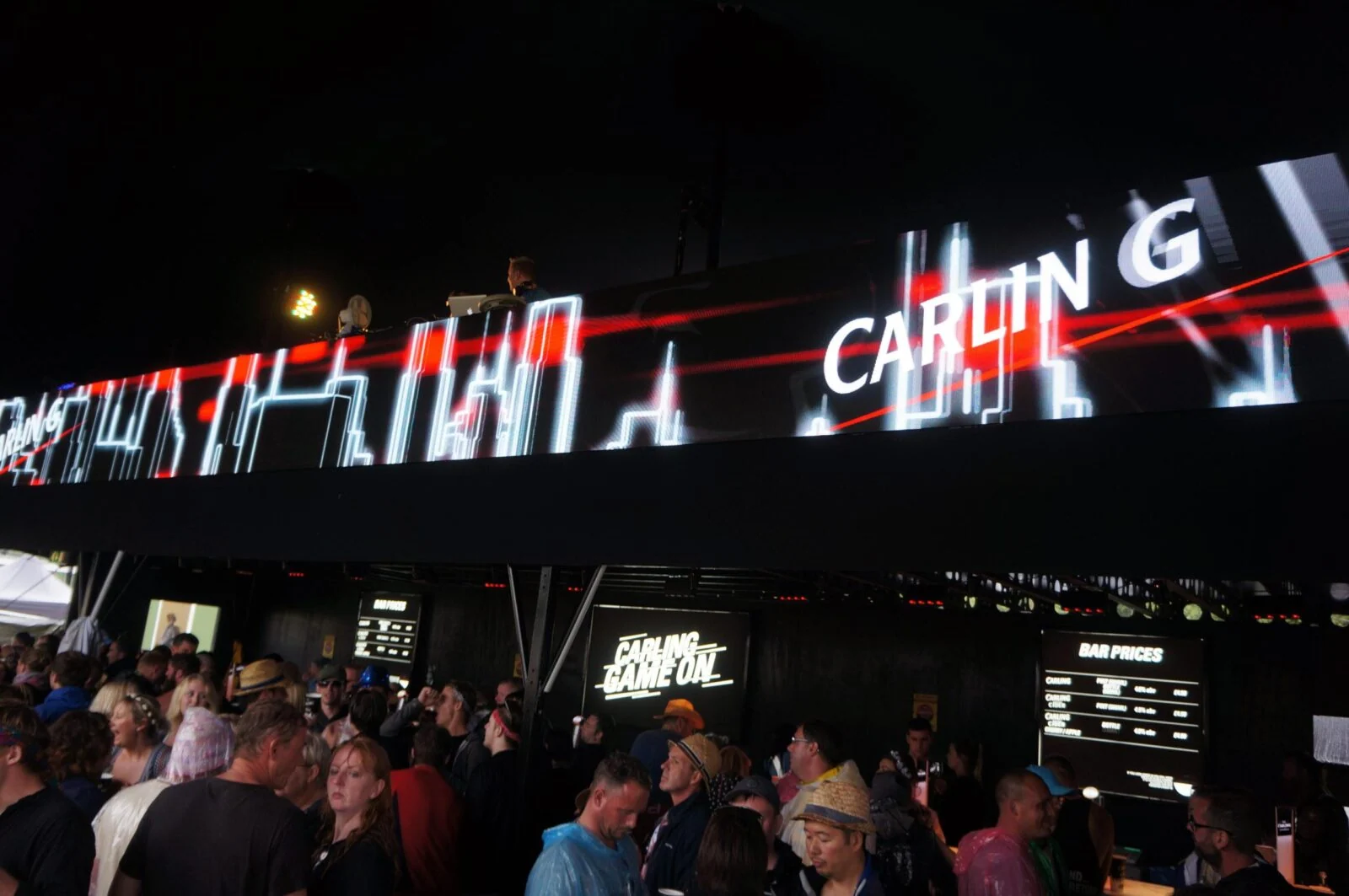 Carling-branded animated light graphics above a busy festival bar.