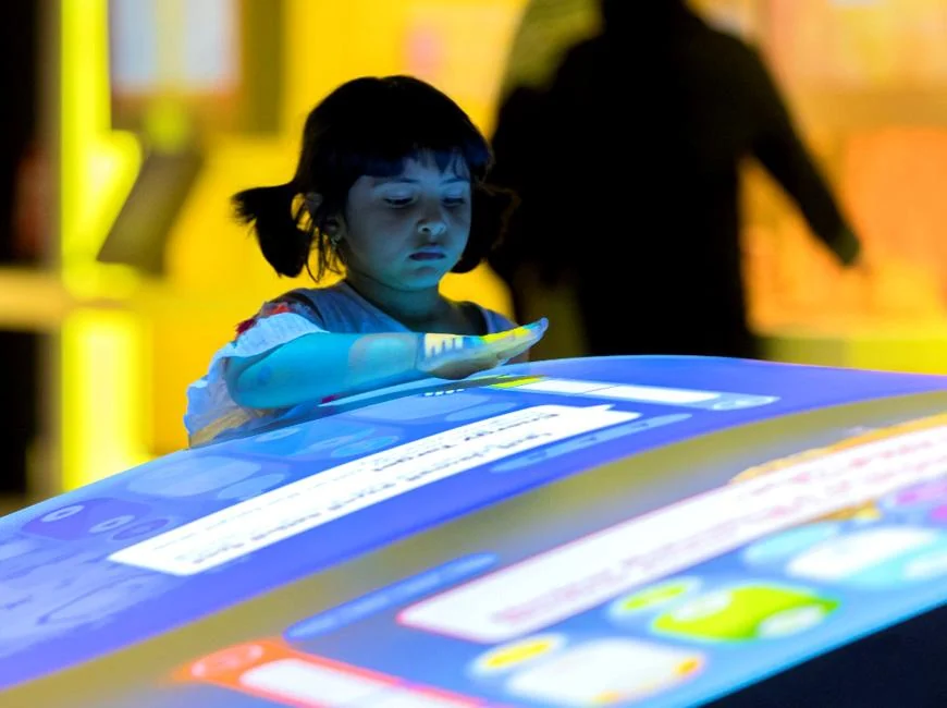 Child reaching over the projected Energy Manager interface on the curved table.