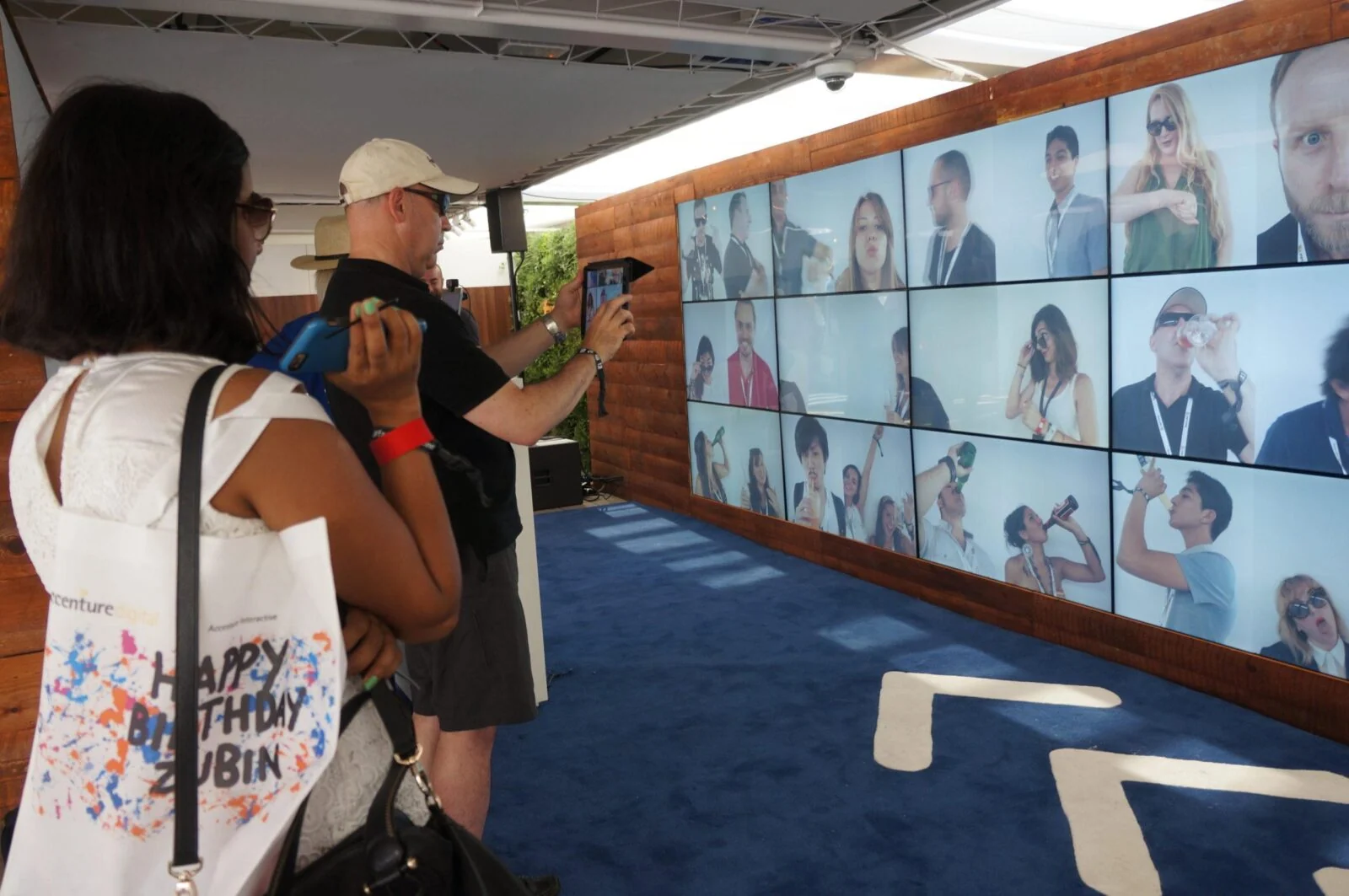 Visitors raising their phones towards the tiled video wall at Facebook zone.