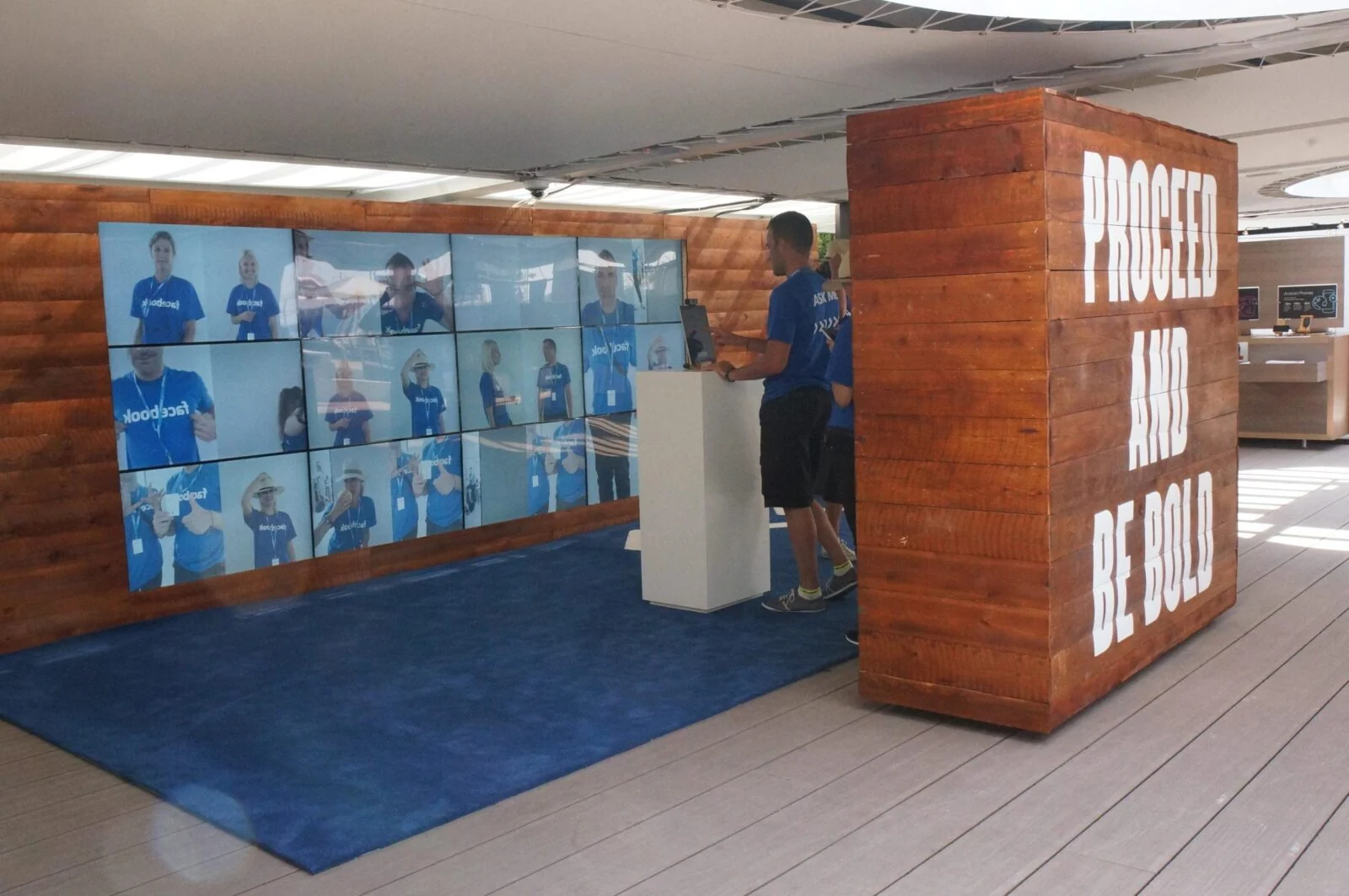 Wood-panelled Facebook zone booth with a video wall, camera kiosk and Proceed and Be Bold message.