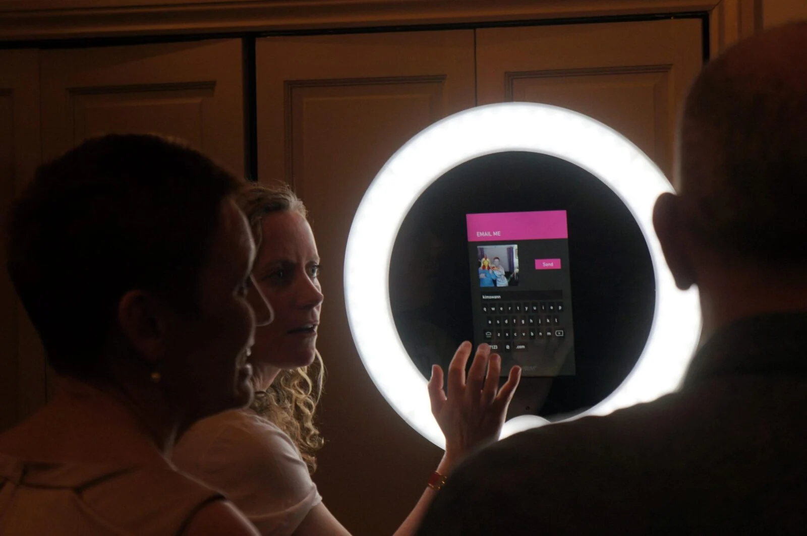 Guests using a Gifstar photo kiosk surrounded by a bright circular light.