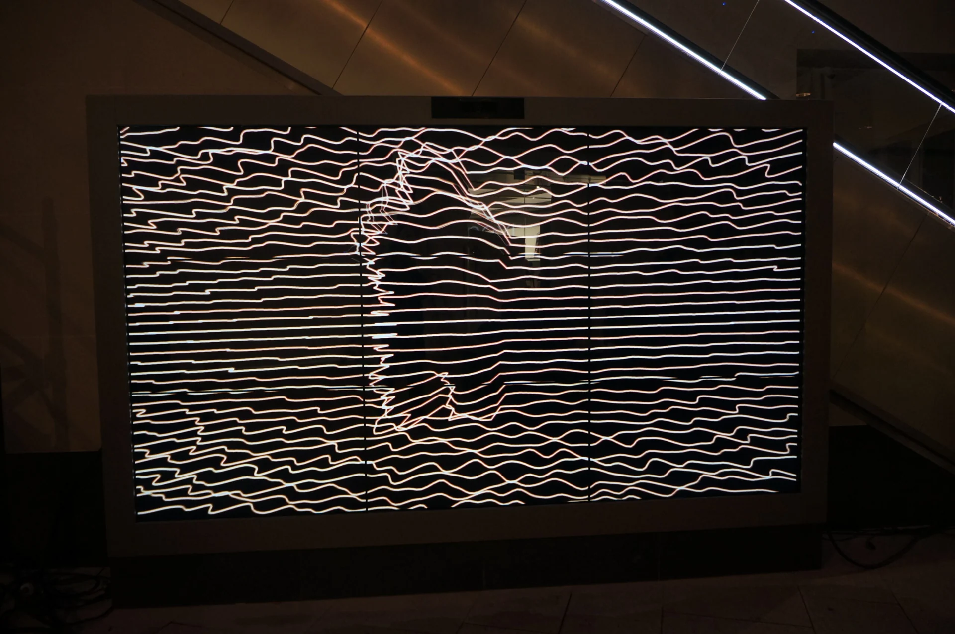 Human silhouette formed from horizontal white lines on an interactive video wall.