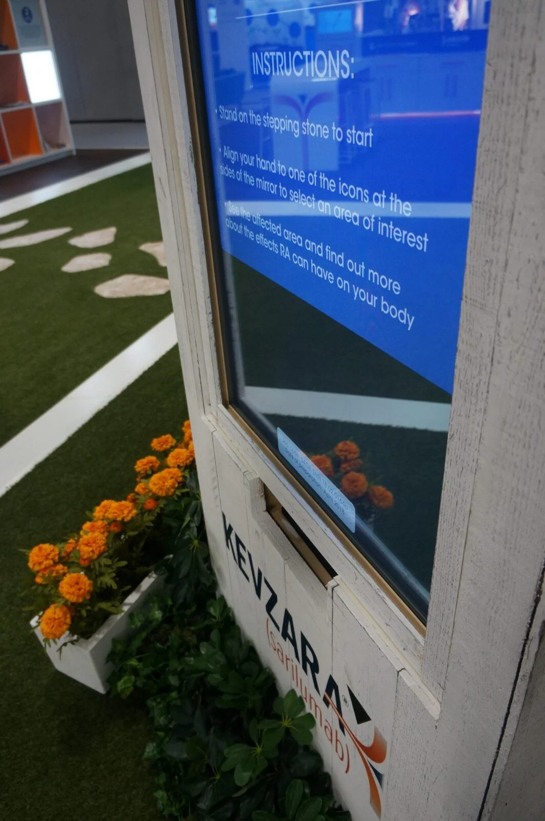 Close-up of the interactive mirror kiosk with a blue instruction panel and Kevzara branding.