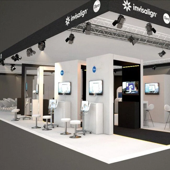 Invisalign exhibition stand with white display columns, screens and stools.