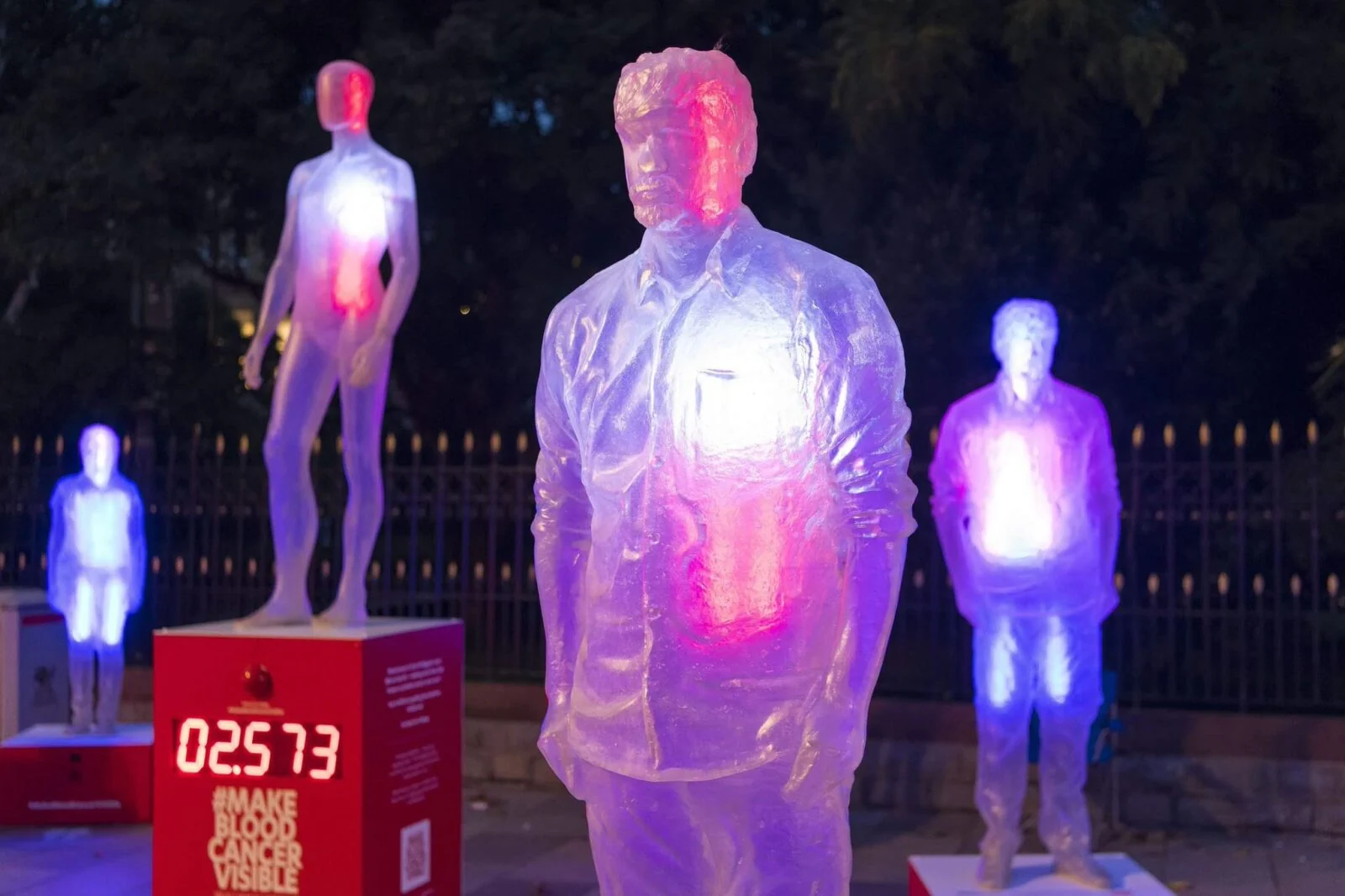 Translucent human figures lit in pink and blue at the Make Blood Cancer Visible installation.