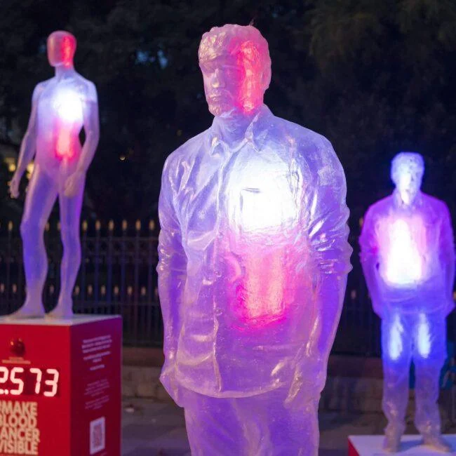 Translucent human figures lit in pink and blue at the Make Blood Cancer Visible installation.