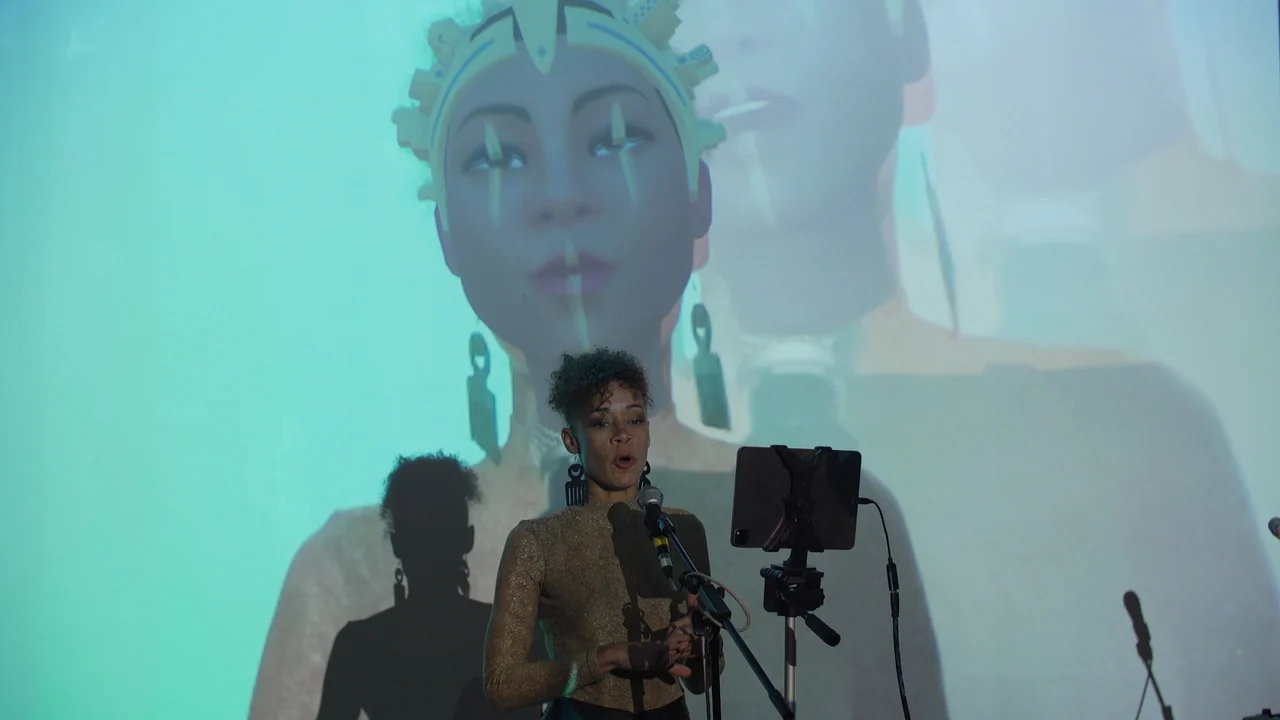 Live performer at a microphone with a large projected digital avatar behind them at Metamirror.