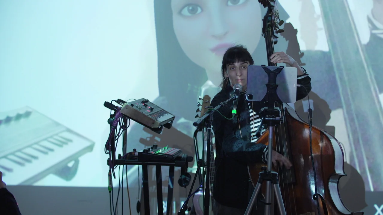 Musician with a double bass and electronic equipment in front of projected Metamirror imagery.