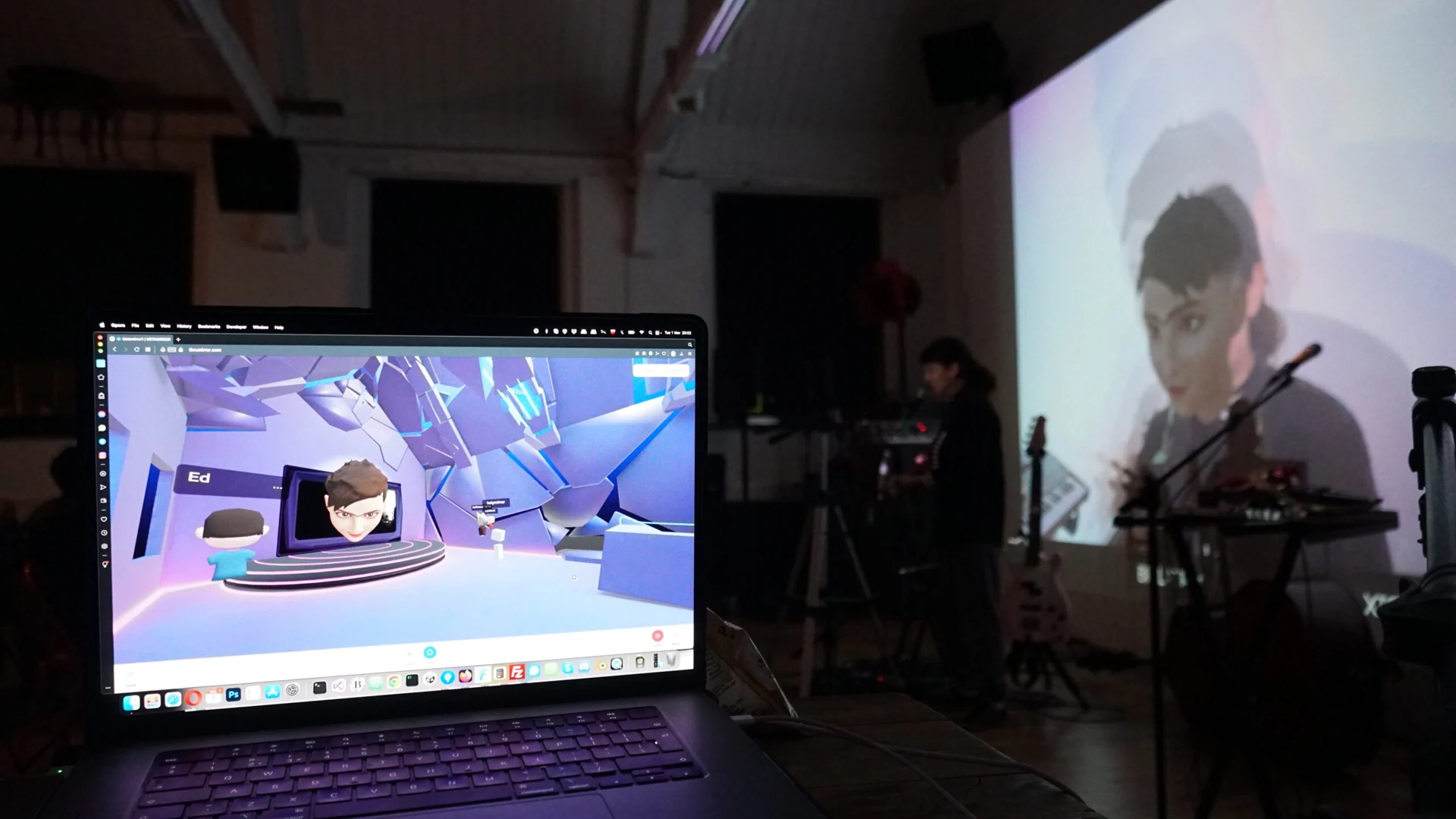 Laptop showing the Metamirror virtual venue beside a live musician and projected avatar.
