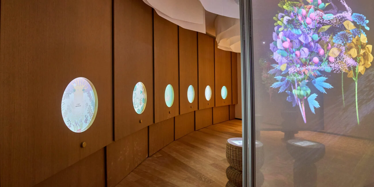 Circular displays along a wooden gallery wall beside a colourful digital flower installation at Poland's Expo 2025 pavilion.