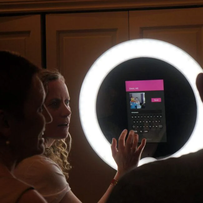 Guests using a Gifstar photo kiosk surrounded by a bright circular light.