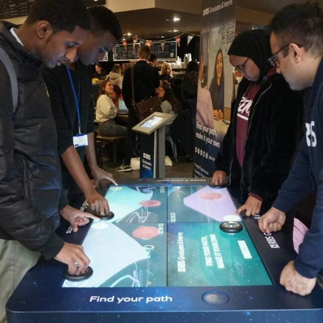 Visitors gathered around the Find Your Path interactive game table.