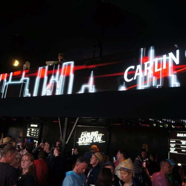 Red and white Carling visuals on a long screen above festival visitors.