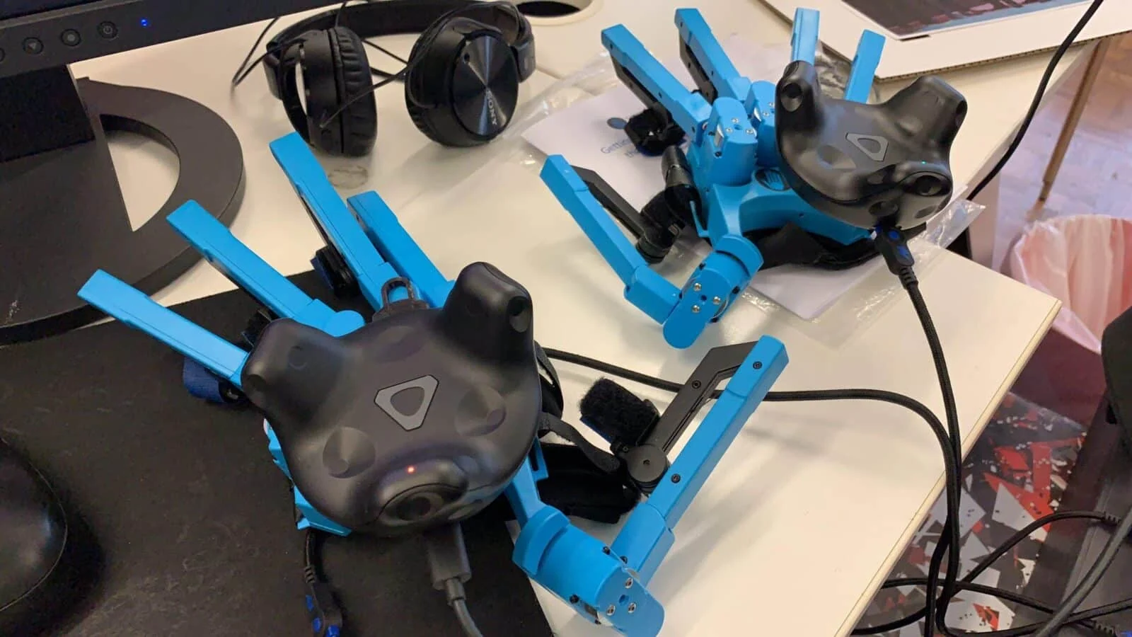 Two blue articulated gloves fitted with tracking devices beside a pair of headphones.