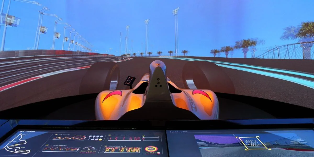 Wide racing simulation display and touchscreen dashboard at an exhibition.