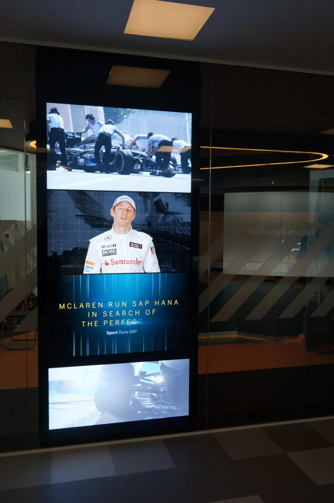Tall stack of screens showing racing footage and driver information at a SAP exhibition.