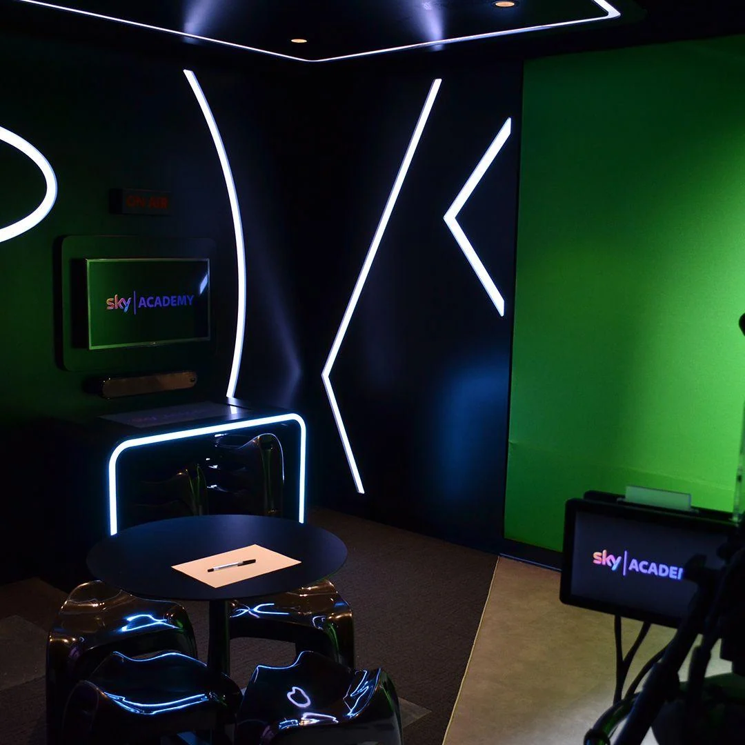 Television studio with a green screen, cameras and white LED light strips.