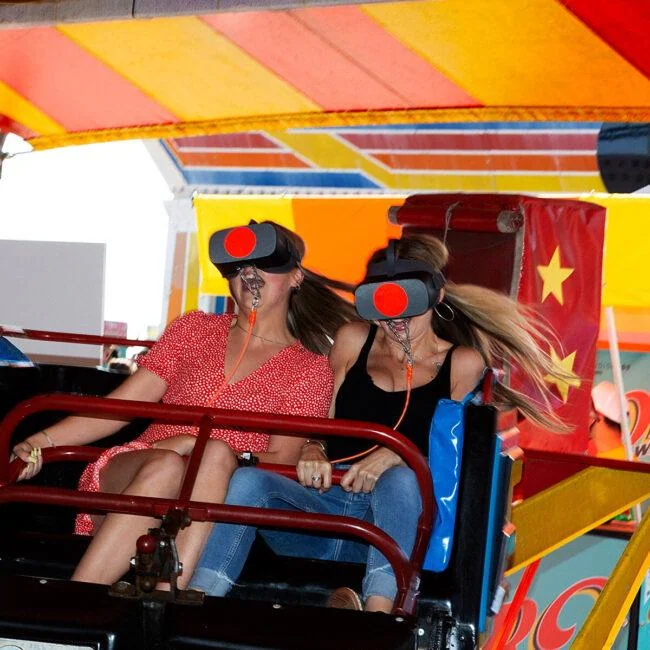 Headset-wearing riders seated behind the safety bar on Brighton Pier's Twister ride.