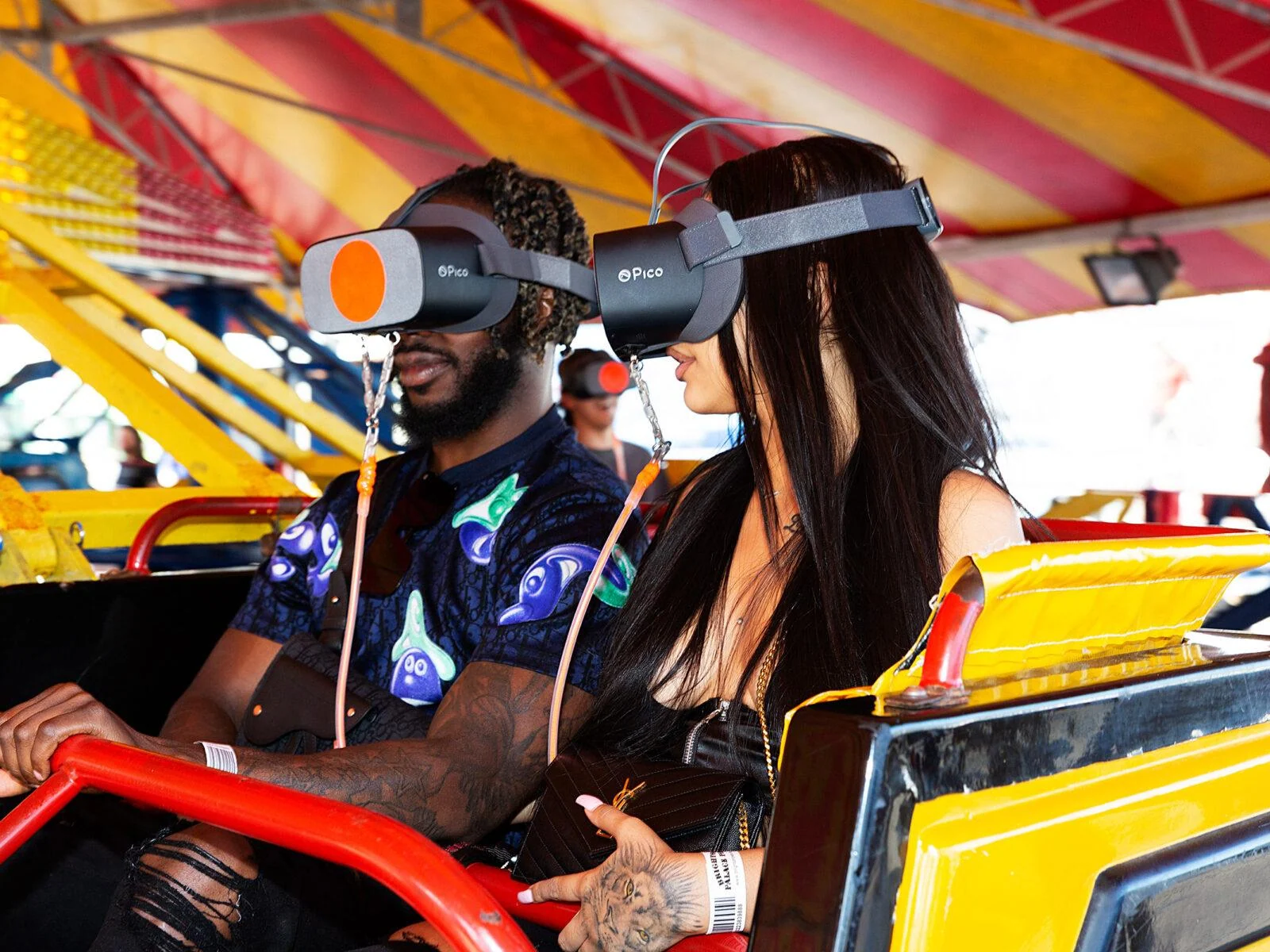 Two participants wearing VR headsets while seated in a yellow Twister ride car.