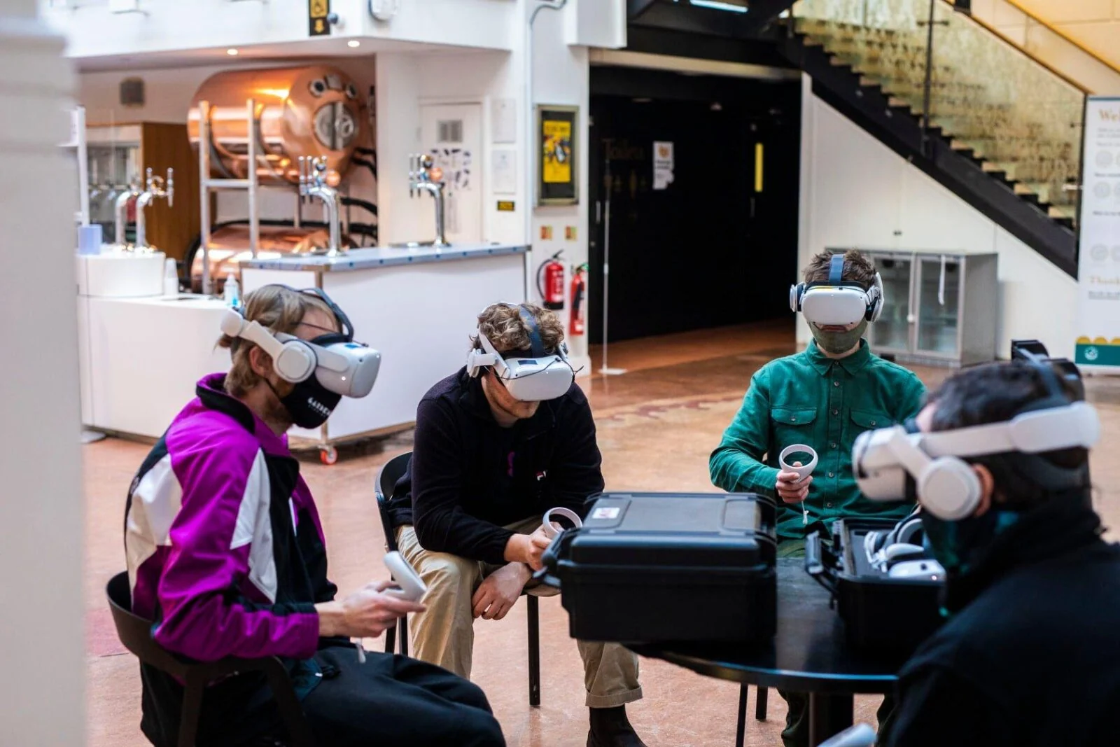 Four participants wearing VR headsets and holding controllers around a table.