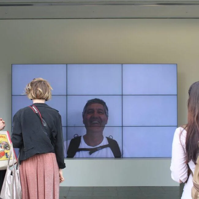 Visitors standing in front of the Smiles Film display at the Serpentine Gallery.